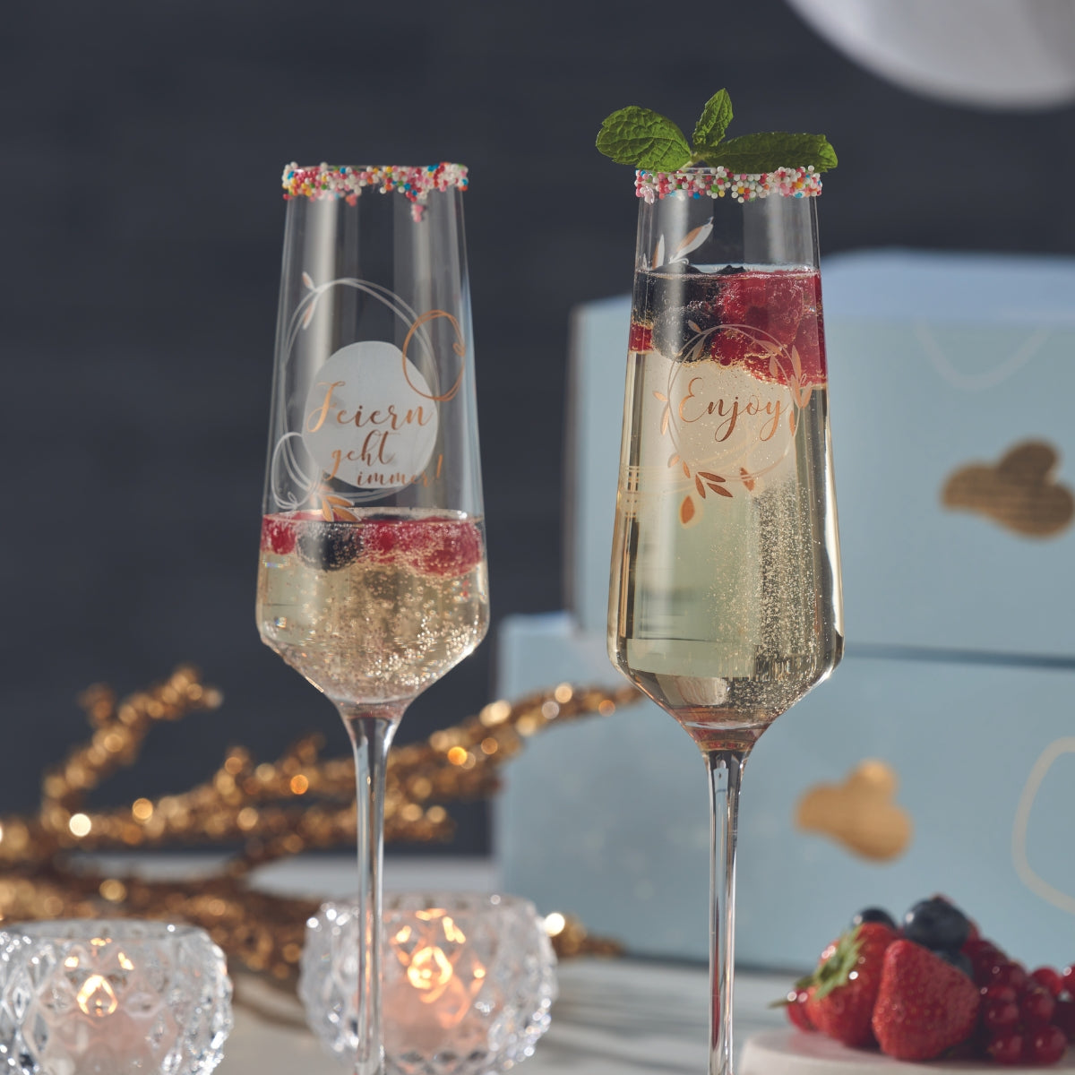 Zwei LEONARDO Sektgläser mit Sekt und Beeren, dekoriert mit buntem Zuckerrand und Minze.