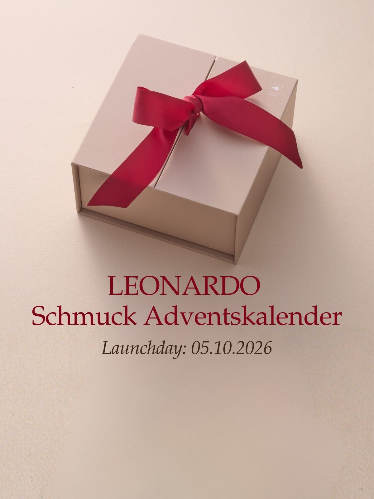 LEONARDO Schmuck Adventskalender, Launchday 05.10.2026. Elegante beige Geschenkbox mit roter Schleife auf hellem Hintergrund