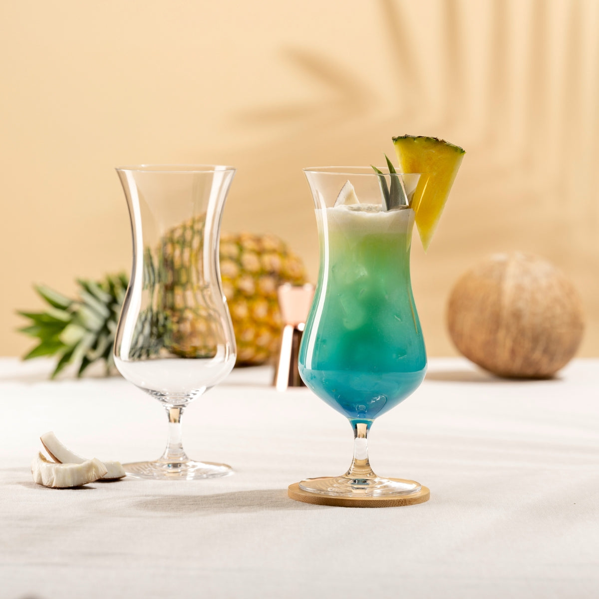 Hurricane-Gläser mit Blue Lagoon Cocktail, Ananas und Kokosnussdeko
