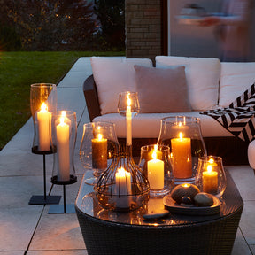 Windlichter GIARDINO mit brennenden Kerzen auf Terrassentisch bei Dämmerung