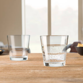 Zwei Trinkgläser EVENT auf Holztisch, eines leer, eines mit Wasser gefüllt