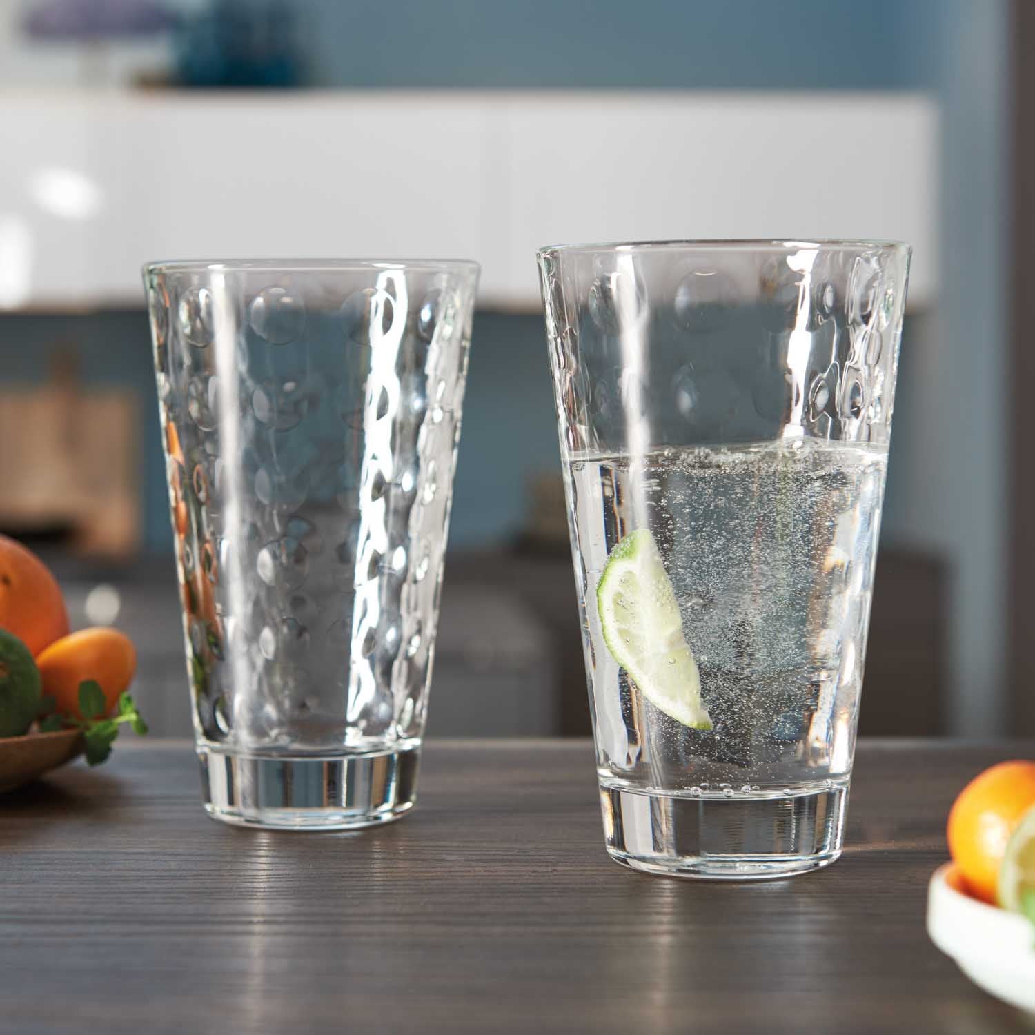 Zwei Trinkgläser OPTIC 540 ml mit Wasser und Zitronenscheibe auf Küchentheke mit Obst