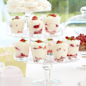 Trinkgläser CIAO mit Erdbeeren und Creme auf Präsentierständer im Freien
