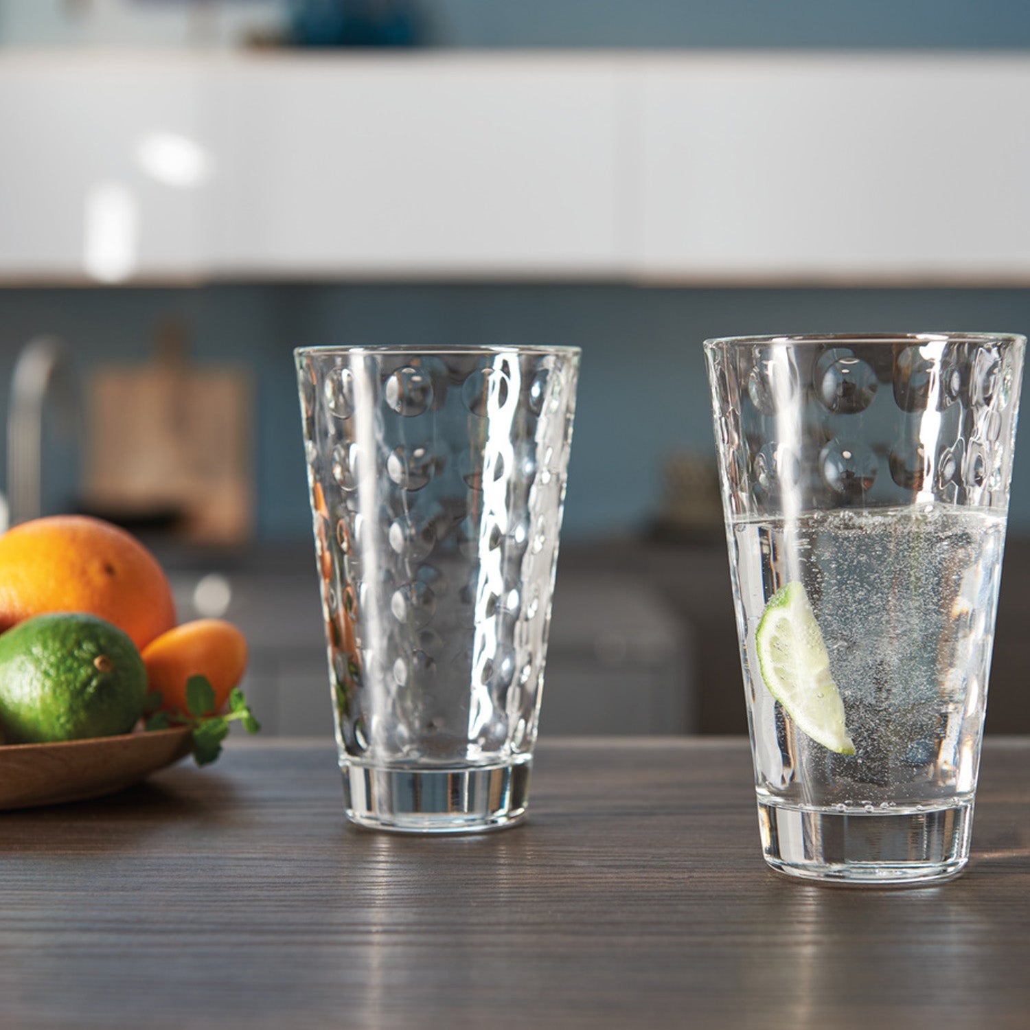 Trinkglas OPTIC 300 ml in Küche, eines gefüllt mit Wasser und Zitrone, Früchte im Hintergrund