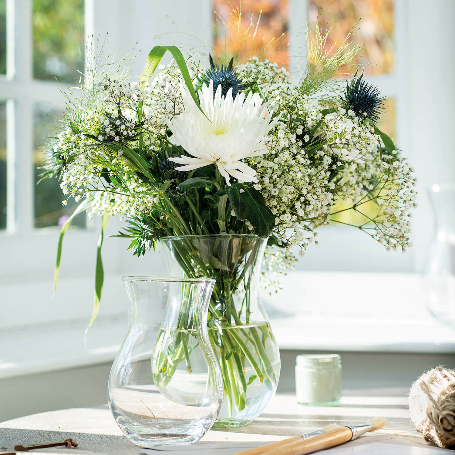 Vase CASOLARE mit weißen Blüten und Schleierkraut am Fenster