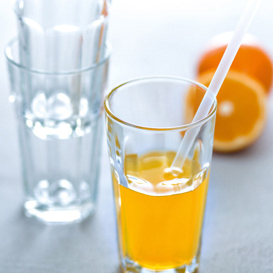 Longdrinkgläser ROCK mit Orangensaft und Strohhalmem, frische Orangenhälften im Hintergrund