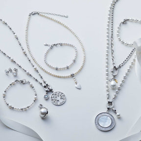 Schmuckkollektion mit Armbändern, Ketten und Anhängern in Weiß und Silber auf neutralem Hintergrund