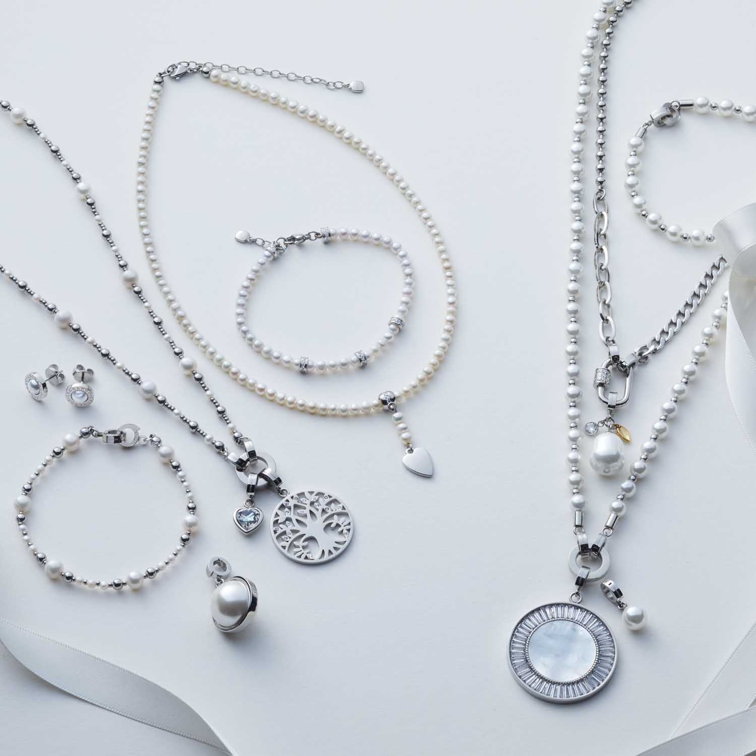 Schmuckkollektion mit Perlenketten, Armbändern und Anhängern in Weiß auf hellem Hintergrund