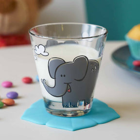Trinkglas BAMBINI mit Elefantenmotiv auf blauem Untersetzer, bunte Perlen daneben