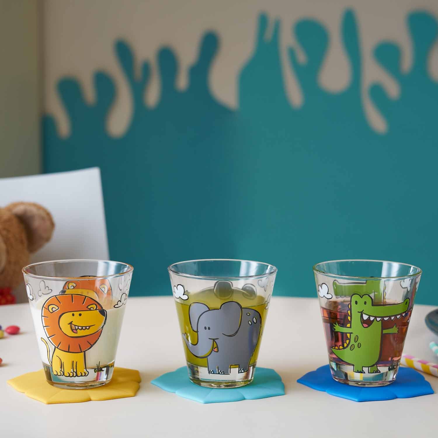 Drei Kinderbecher BAMBINI mit farbigen Tiermotiven auf Untersetzer