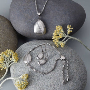 Silberschmuck der Serie CIOTTOLO auf Steinen mit gelben Blüten