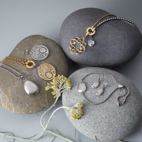 Schmuckkollektion auf Steinen mit Armbändern und Anhängern in Gold und Silber