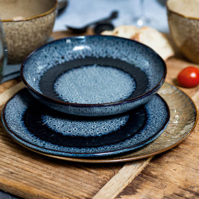 Blaue Keramikteller gestapelt auf Holzuntergrund, gedeckter Tisch