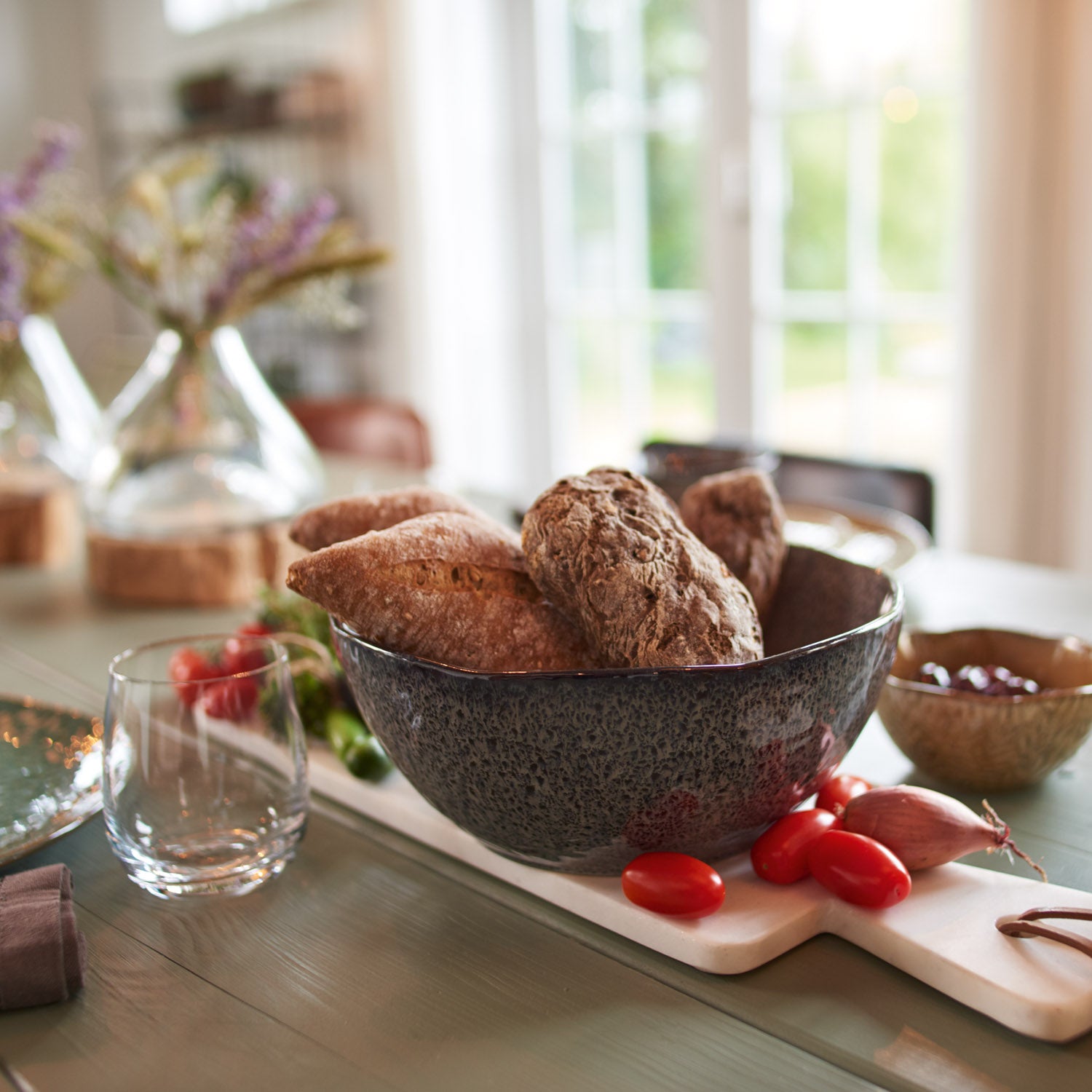 Keramikschale MATERA mit Schokoladenkuchen auf Kuehlentisch mit Blumen und Glas