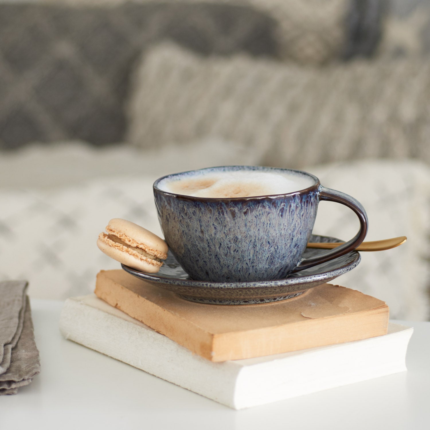 Keramiktasse MATERA anthrazit mit Kaffee auf Bücherstapel und Makronen, Wohnzimmer