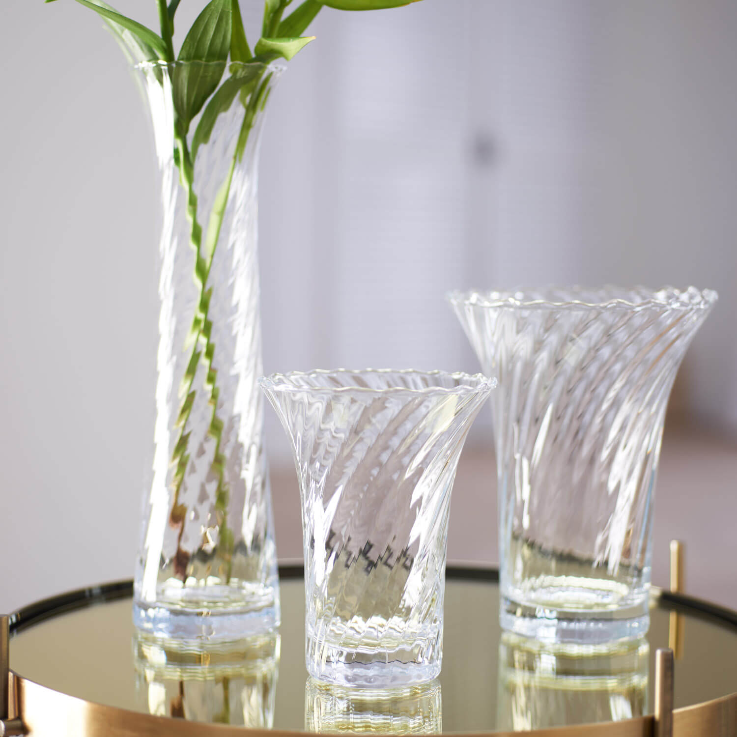 Vase RAVENNA mit Blumen auf Glastisch, daneben zwei Gläser