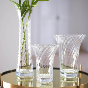 Vase RAVENNA mit Blumen auf Glastisch, daneben zwei Gläser