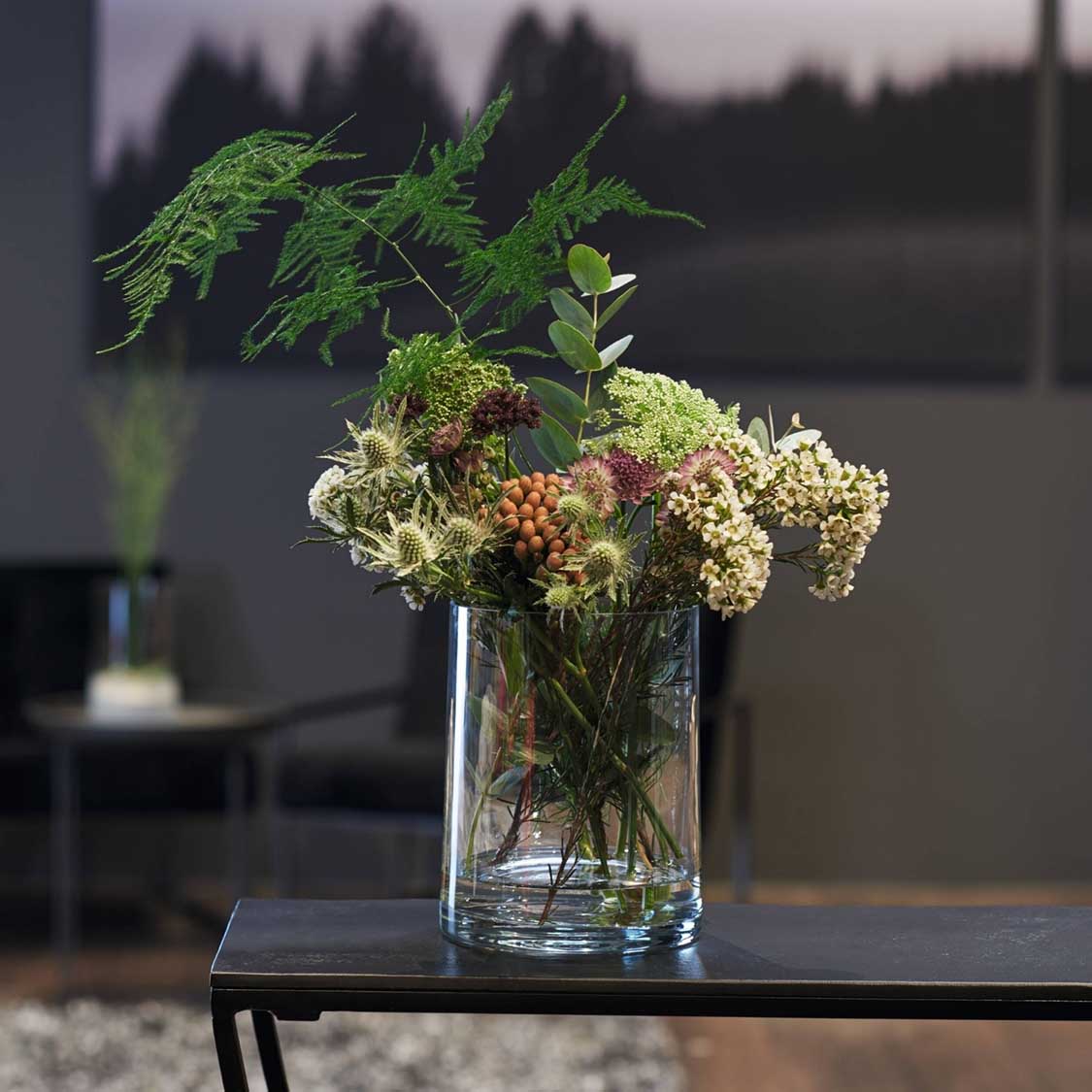 Glasvase NOVARA gefüllt mit Blüten und grünen Zweigen auf schwarzem Tisch