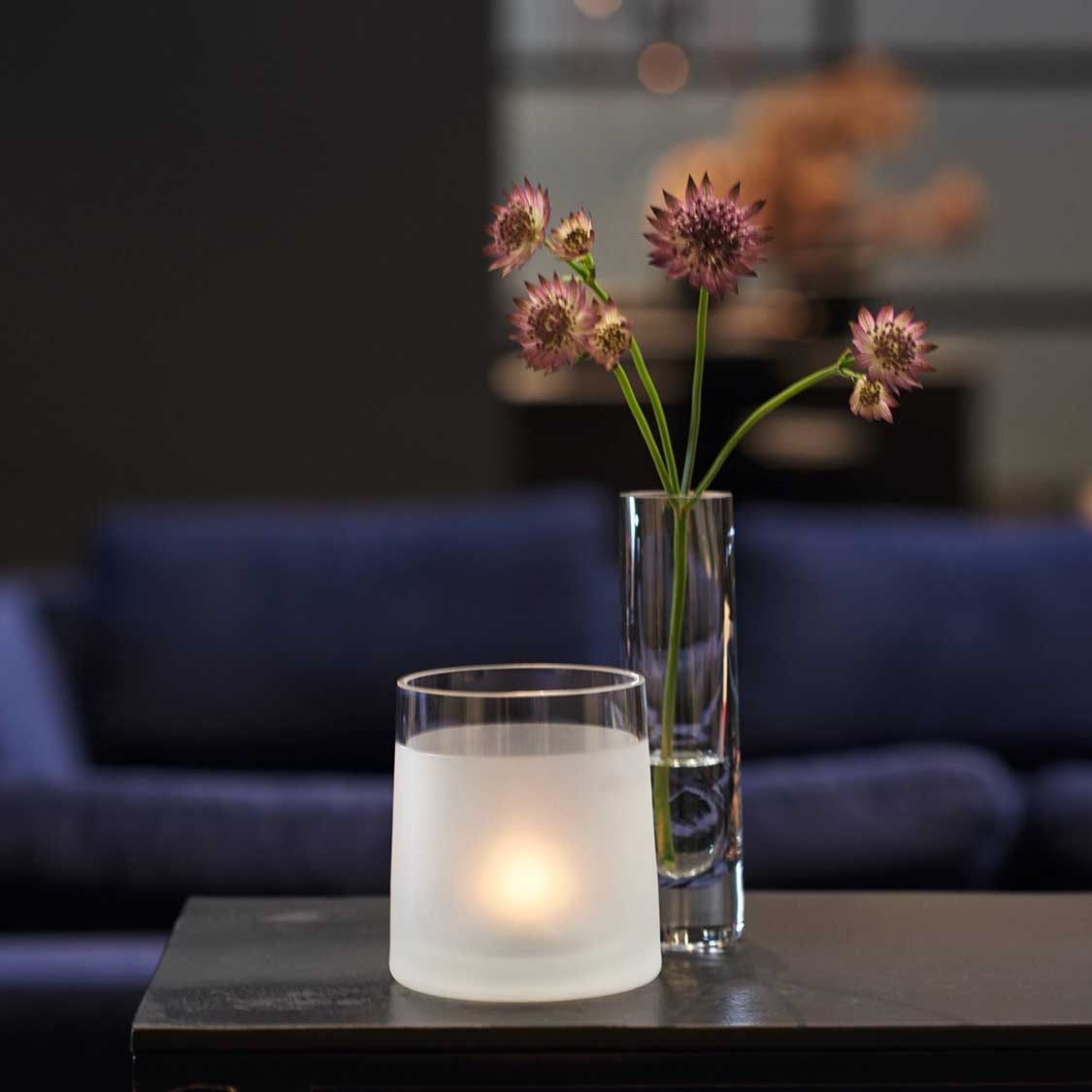Solifleurvase NOVARA mit rosa Blüten, Teelicht und Sofa im Wohnzimmer