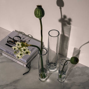 Solifleurvase NOVARA mit Mohnkapseln und weißen Blüten auf Marmortisch, Styling mit Buch und Schmuck