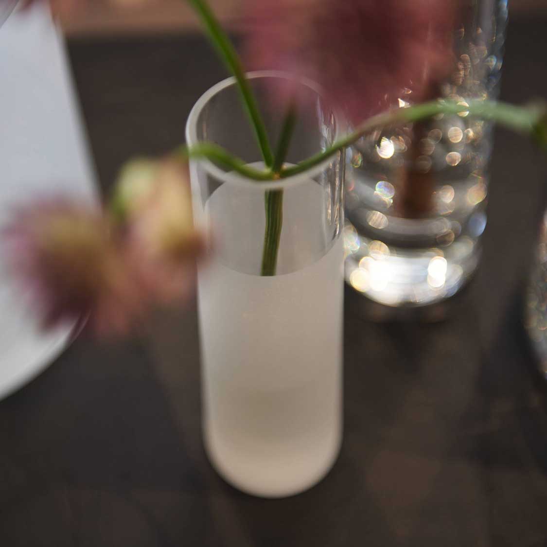 Solifleurvase NOVARA mit Grashalm, auf gedecktem Tisch neben Gläsern