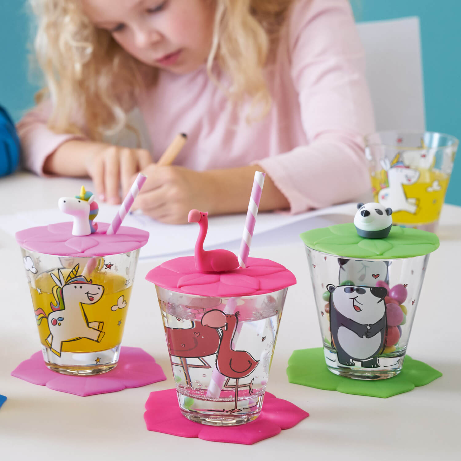 Kind malt mit drei farbigen Silikondeckeln auf Gläsern mit Motiven