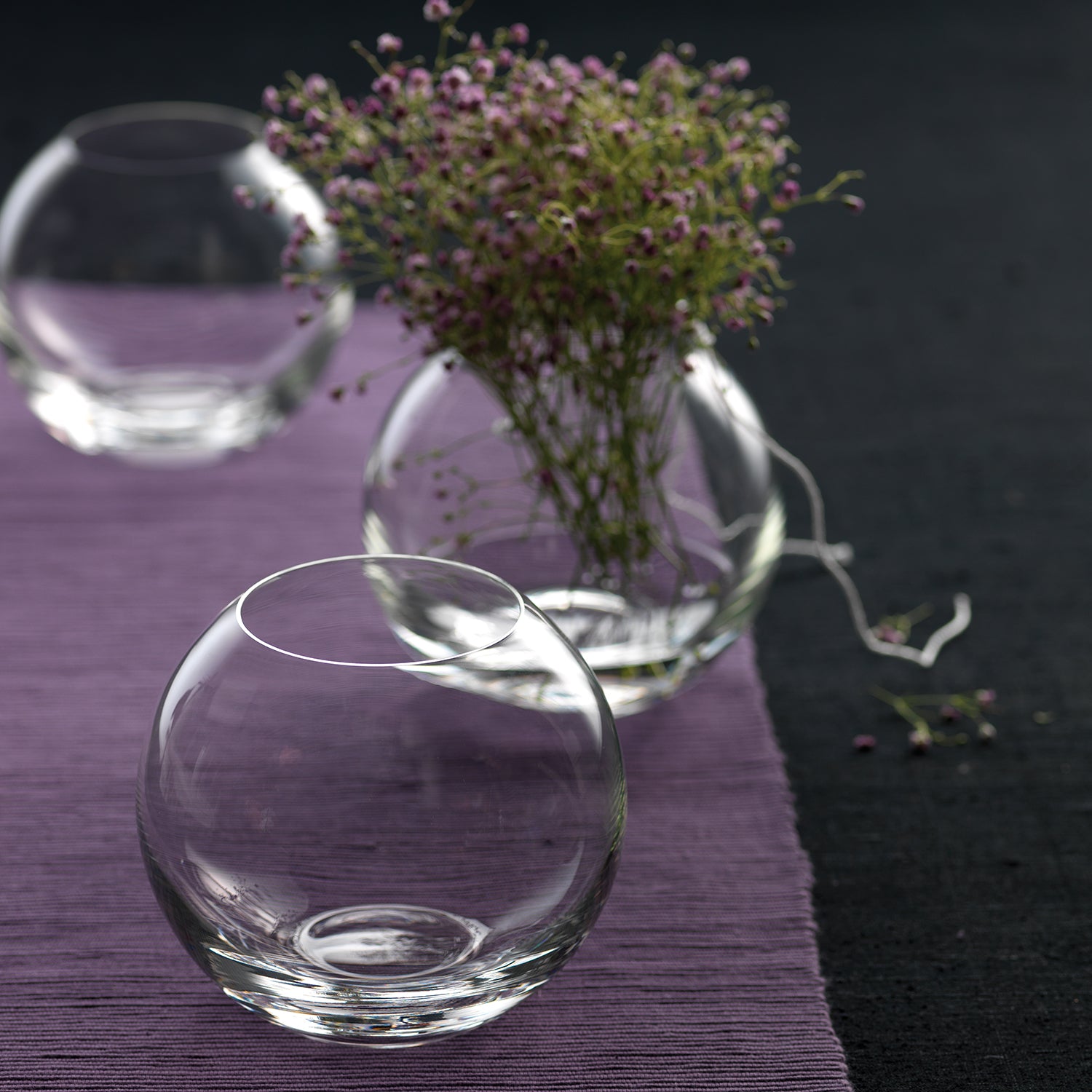 Glasvase BOCCIA mit lila Blüten auf dunklem Untergrund