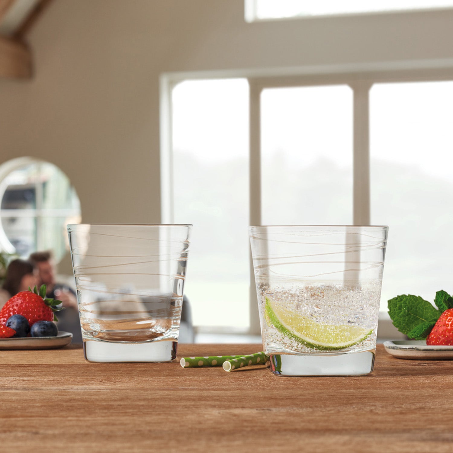 Trinkglas VARIO 250 ml mit Getränken auf Holztisch, Beeren und Minze daneben, helle Fenster im Hintergrund