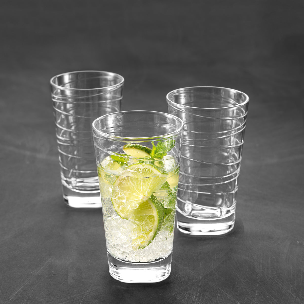 Drei Trinkgläser VARIO 280 ml, eins gefüllt mit Zitronenlimonade und Minze, zwei leere, auf grauem Untergrund