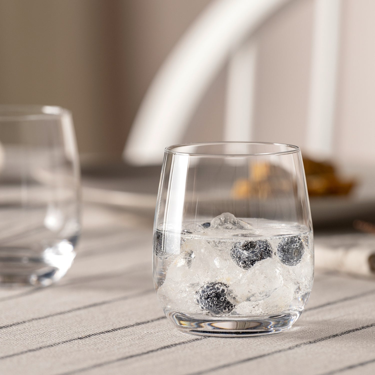 Trinkglas TIVOLI mit Eiswürfeln auf sonniger Terrasse, weitere Gläser im Hintergrund