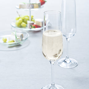 Sektglas TIVOLI mit Champagner gefüllt auf gedecktem Tisch mit Obst und Käse