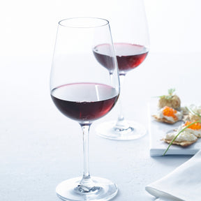 Rotweinglas TIVOLI mit Rotwein gefüllt, Tischgedeck mit Appetithäppchen im Hintergrund