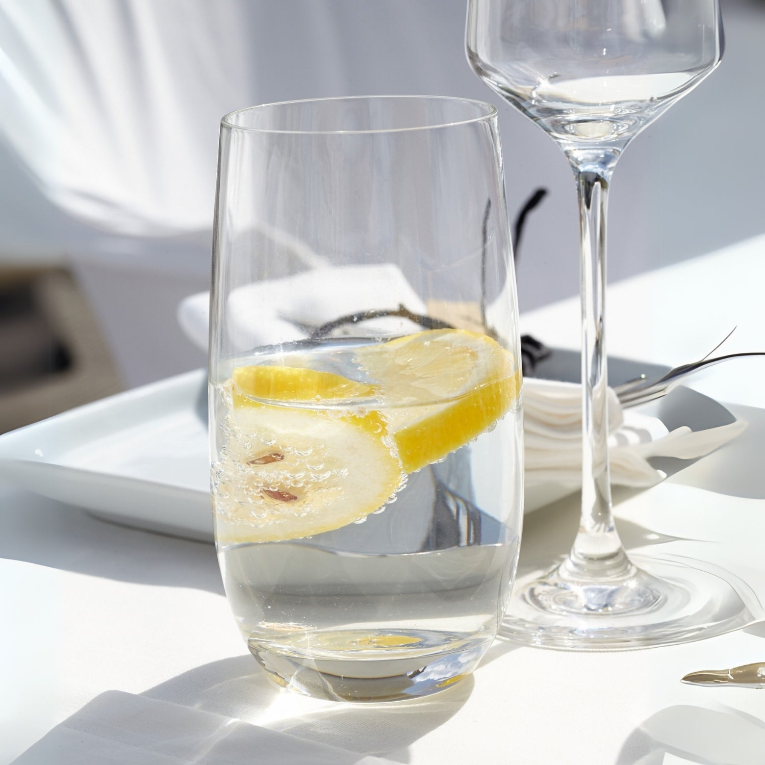 Trinkglas TIVOLI mit Wasser und Zitronenscheibe auf gedecktem Tisch