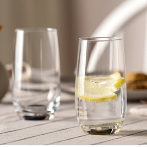 Trinkglas TIVOLI mit Zitronenscheibe auf gedecktem Tisch, daneben leeres Glas