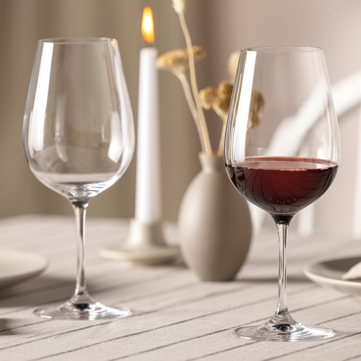 Rotweinglas TIVOLI mit Rotwein gefüllt auf gedecktem Tisch neben leerem Glas