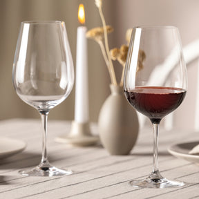 Rotweinglas TIVOLI mit Rotwein gefüllt auf gedecktem Tisch neben leerem Glas