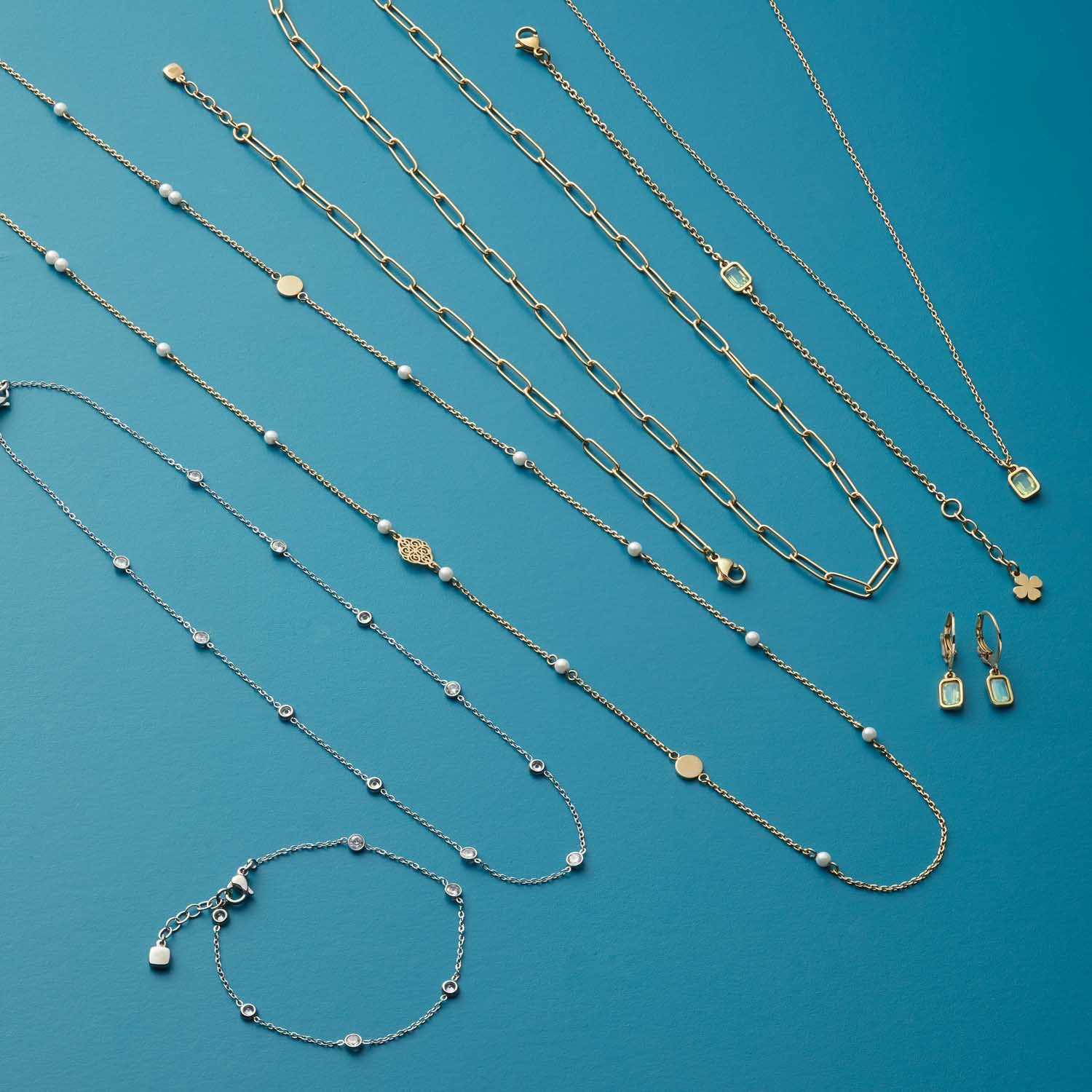 Schmuckkollektion aus Glas auf blauem Hintergrund mit Halsketten, Armband und Ohrringen