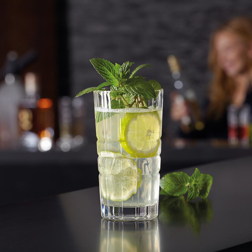 Longdrinkglas SPIRITII gefüllt mit Wasser, Limettenscheiben und Minze, Barszene im Hintergrund
