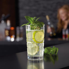 Longdrinkglas SPIRITII gefüllt mit Wasser, Limettenscheiben und Minze, Barszene im Hintergrund