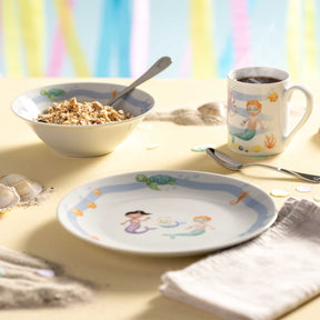 Kindergeschirr BAMBINI AVVENTURA mit Meermotiven auf gedecktem Tisch, Schale mit Müsli und Becher mit Kaffee