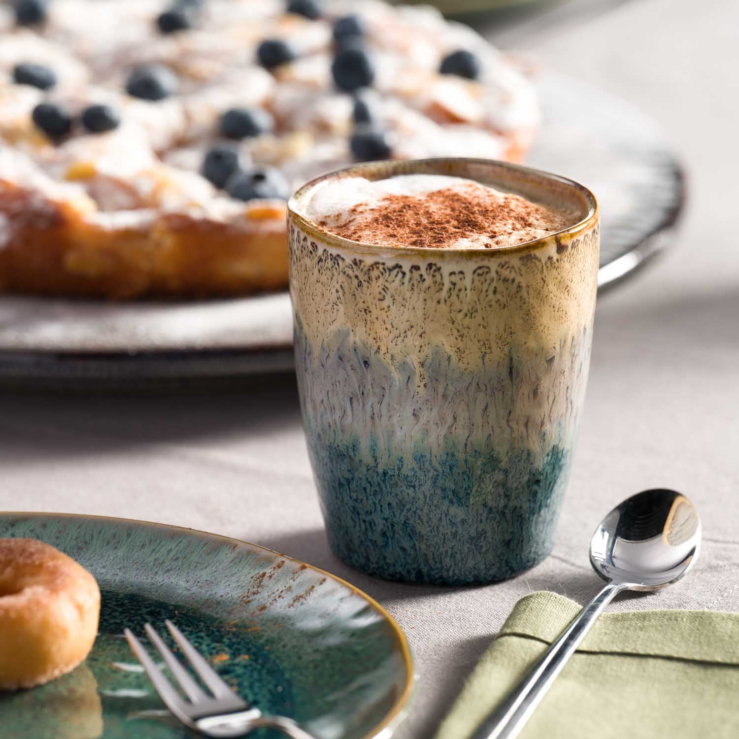 Becher MATERA mit Kaffee auf gedecktem Tisch mit Kuchen