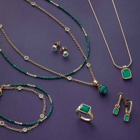 Grüne Glasschmuckkollektion mit Ring SUSA 17, Halsketten, Ohrringen und Armband auf violettem Hintergrund