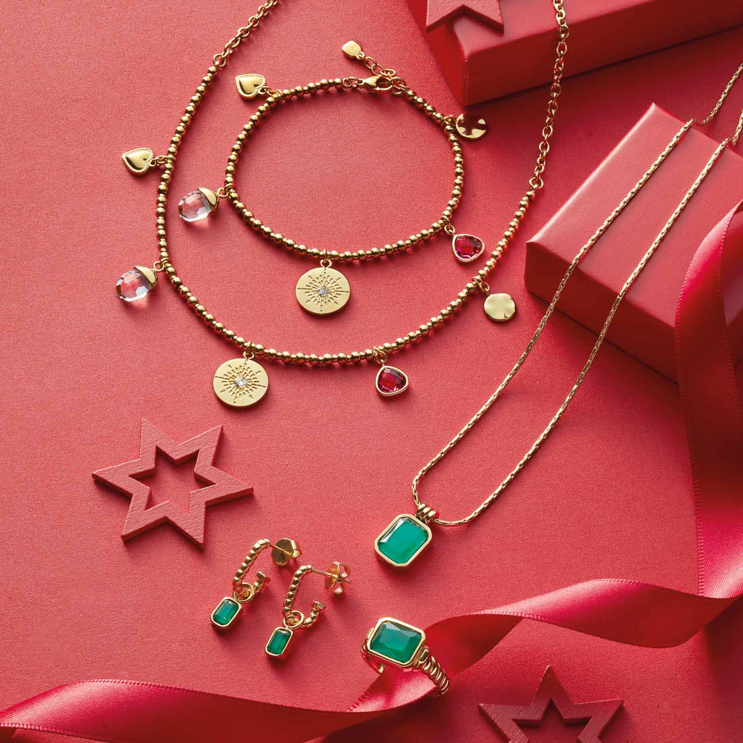 Schmuckkollektion mit grünen Glaselementen, Ketten, Armbändern und Ohrringen auf rosa Hintergrund mit Dekorationselementen