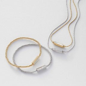Halskette Pilea gold und Armband in Gold- und Silberfarben auf weißem Untergrund