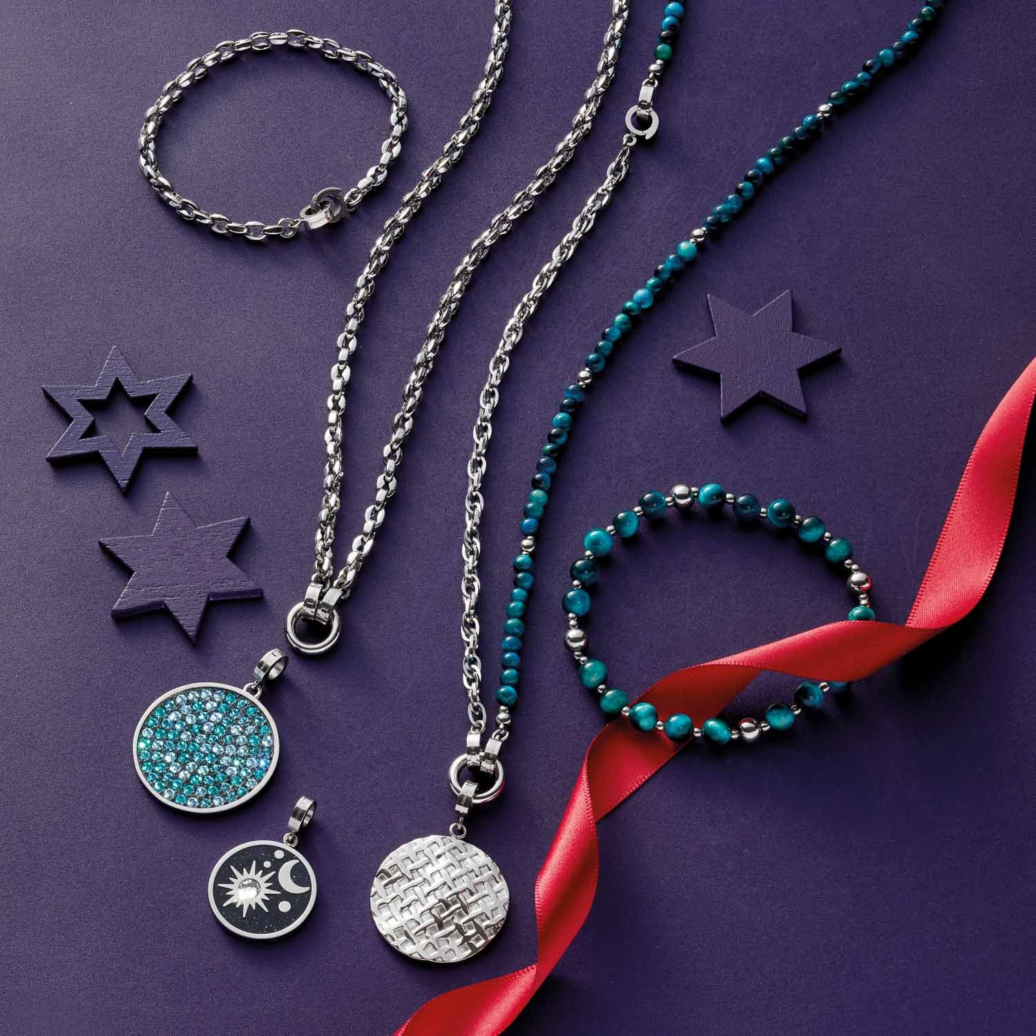 Halskette ROMEA mit Schmuckanhängern, Armbändern und Dekosternen auf violettem Untergrund