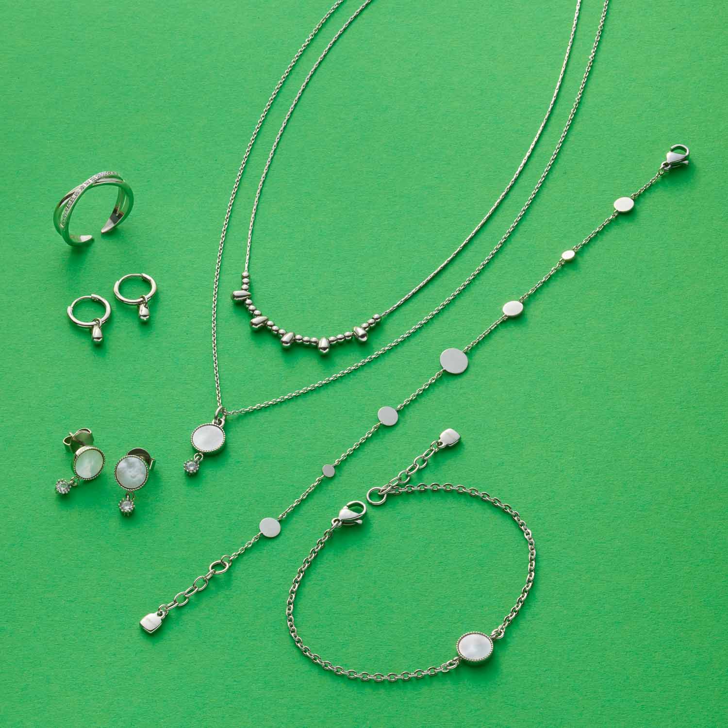 Halskette AMALIA, Ringe und Armbänder aus Edelstahl auf grünem Hintergrund
