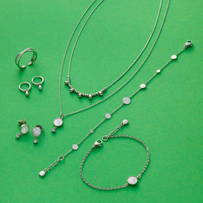 Halskette AMALIA, Ringe und Armbänder aus Edelstahl auf grünem Hintergrund