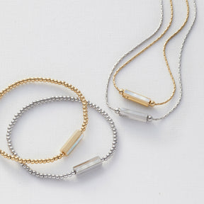 Armband PILEA gold und silber mit Perlenband und Metallzylinder auf weißem Untergrund