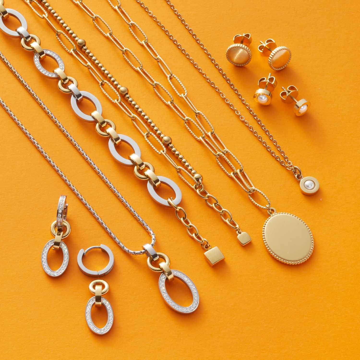 Schmuckkollektion der Serie LENA auf gelbem Hintergrund, Ketten, Armbänder, Ohrringe und Anhänger aus Edelstahl