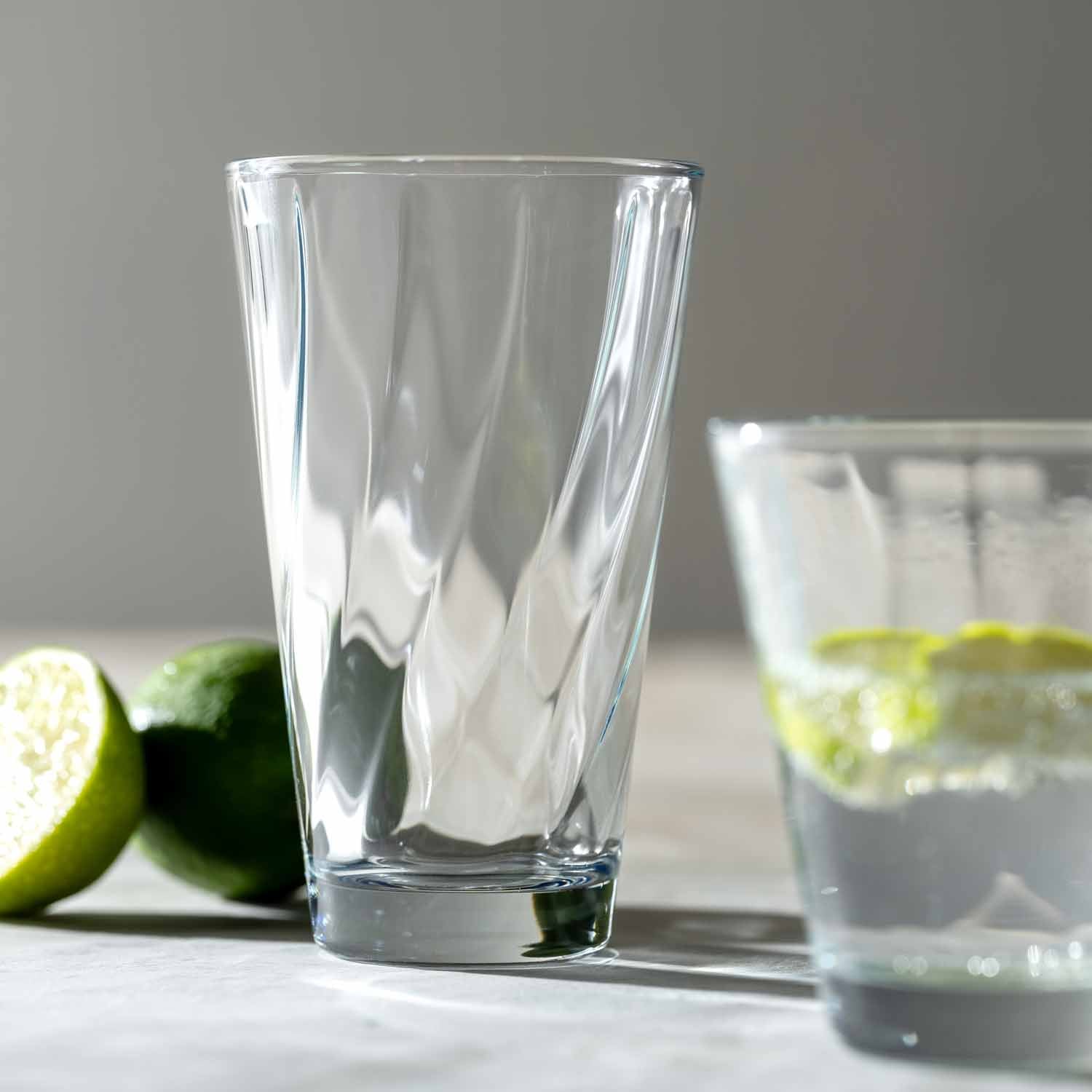 Trinkglas TWIST mit Limetten auf weißem Untergrund, gefülltes Glas im Hintergrund